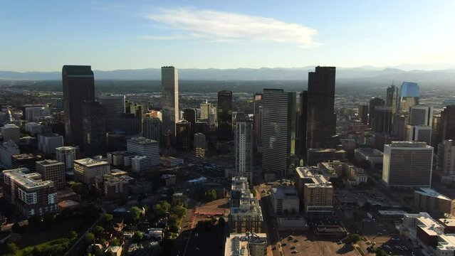 Aerial cinematic drone mid summer early fall Downtown Denver Colorado mile hight city buildings traffic wisp clouds blue sky afternoon sunset stunning golden hour light circling pan to the left motion