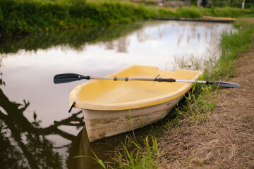 Yellow boat with paddle floating on calm water. Solitude, calmness and relaxation