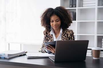 Businesswoman using a tablet to analysis graph company financial in office.