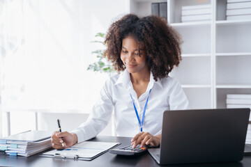 Female businessman working with holding a pen and using a calculator to calculate the numbers of...