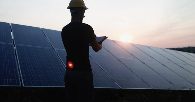 Young engineer man working at solar panel factory outdoor while using digital tablet - Renewable green energy and environmental concept