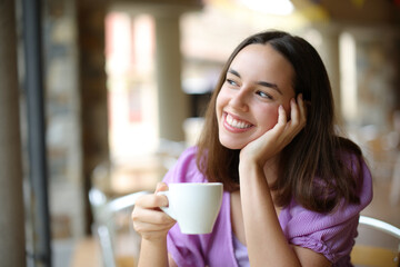 Dreamer woman drinking coffee and dreaming in a bar