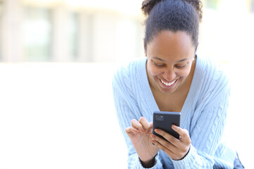 Happy black woman using phone on white