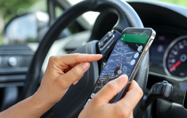 Female driver hand holding a phone with interface navigator on a screen.