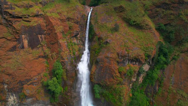Aerial revealing tilt down view Chyamche waterfall and river. Annapurna circuit trek. Himalayas mountains range. Nepal famous sightseeing trekking destination.