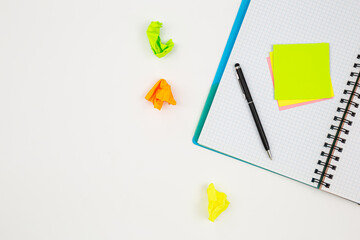 Notebook, pen and paper colored reminders on a white background.