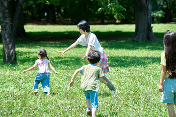 追いかけっこをして遊ぶ子供たちとエプロン姿の女性