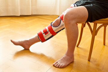 Adjustable knee immobilizer or leg brace on a male patient, used for fixation of the knee joint as...