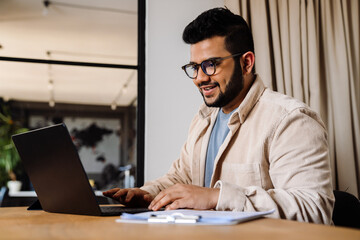 Fototapeta na wymiar Smiling business man working on laptop while sitting in office
