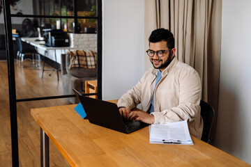Fototapeta na wymiar Smiling business man working on laptop while sitting in office