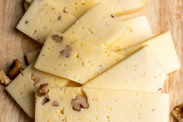 Sliced piece of milk cheese with walnuts