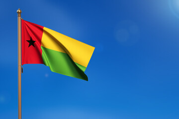 Guinea Bissau. Flag blown by the wind with blue sky in the background.