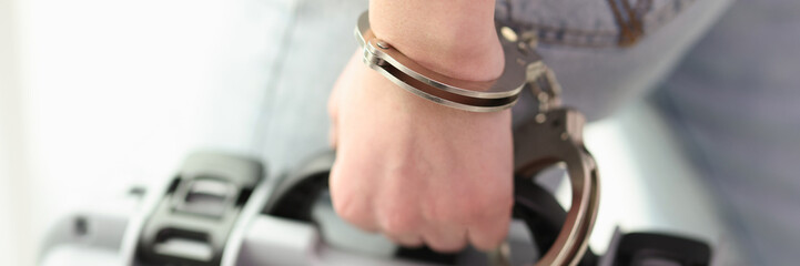 The hand is handcuffed to the baggage, a close-up