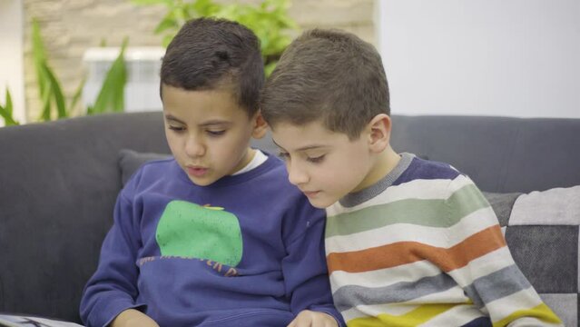 two twin brothers reading a story in the living room of the house