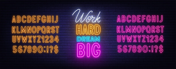 Work Hard Dream Big neon lettering on brick wall background.