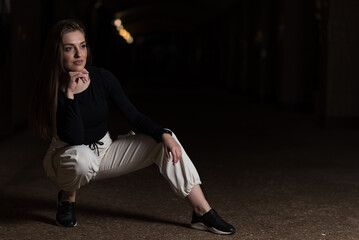 Portrait of a girl in sportswear in a dark underpass. Happy girl posing.