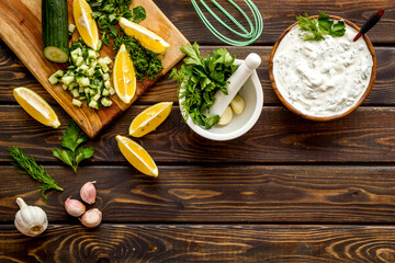 Greek dip sauce sour cream with herbs and cucumber. Cooking on kitchen table