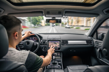 Man touching screen of a GPS navigation system in his car.