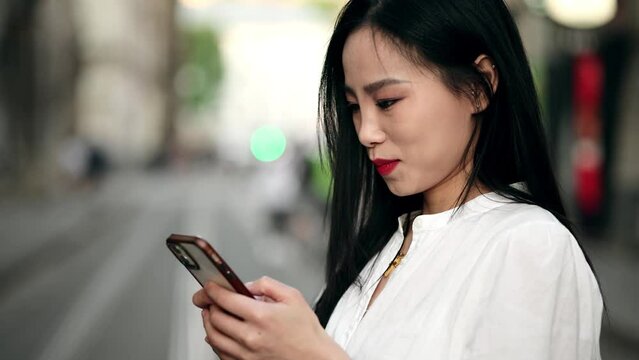 Young beautiful asian woman smiling confident using smartphone at street
