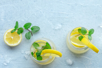 Lemonade with mint panorama. Lemon water drink with ice. Two glasses and lemons on a pastel background, shot from the top with a place for text. Detox beverage. Fresh homemade cocktail