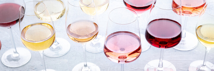 Wine glasses at a tasting panorama. Rose, red, and white wine, drinks on a table. An assortment of wines of many different colors, panoramic banner for a menu