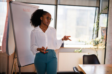 Businesswoman present her idea to working team. African businesswoman in conference room.