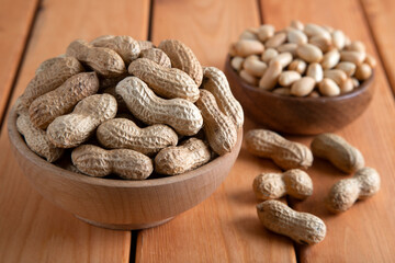 Bowl full of shelled and roasted peeled peanuts on wooden background