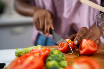 Young African woman in kitchen. Close up of woman making salad.