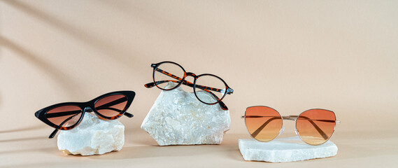 Sunglasses and glasses sale concept. Glamour sunglasses on stones on beige background with shadows. Trendy Fashion summer accessories. Copy space. Eyewear sale, promotion. Optic store discount poster