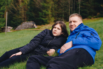 Father laying on his back in the grass with her young daughter. Parenthood and childhood family concept outdoors in nature. happy father and little girl on the grass. Devoted father and daughter lying