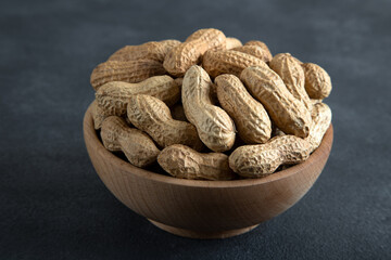 Bowl full of shelled peanuts on dark background