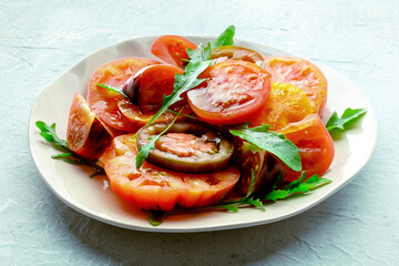 Fresh tomato and rocket salad. A variety of tomatoes of different sorts with arugula leaves. Healthy summer food