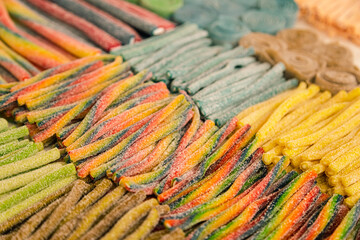 Arrangement of sweets on a market stall, showing candy laces and liquorice strings in a variety of rainbow colors.