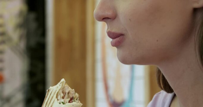 Beautiful young woman eating tasty fresh shawarma, closeup