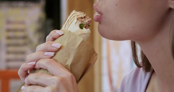 Beautiful young woman eating tasty fresh shawarma, closeup