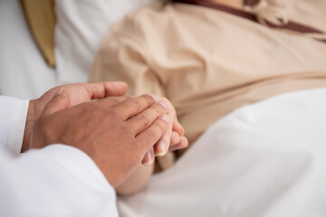 Fototapeta na wymiar Closeup hands of doctor man encourage with elderly patient at the hospital, physician take care and holding hands for consoling senior sick, diagnostic disease and illness, medical concept.