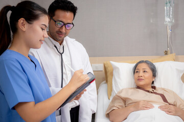 Specialist doctor and nurse explaining and check with elderly patient in hospital, medical and sick, diagnostic with report medical and health care on tablet, examining disease, senior and unwell.