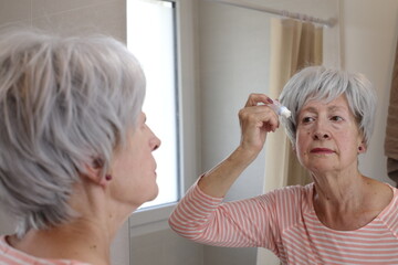 Senior woman using eye drops 