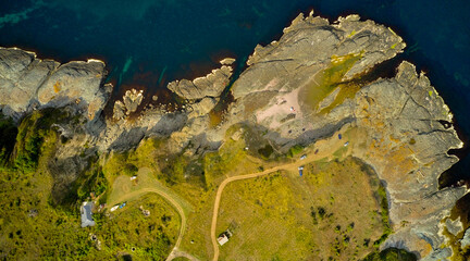 People swim in the azure clear sea in the bay among the rocky shore. Drone photo