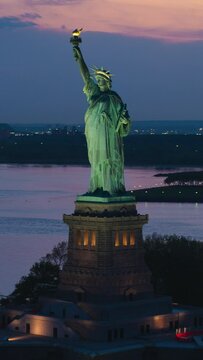 Vertical Screen: Aerial Fly-By Around the Statue of Liberty. Helicopter Footage of the Patriotic Monument in Beautiful Sunset Setting, Standing on a Liberty Island in New York City Harbor