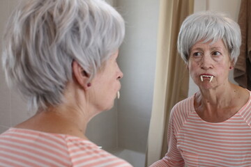 Senior woman wearing spooky vampire fangs 