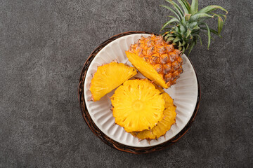 Fresh cut pineapple with tropical leaves on gray table background.