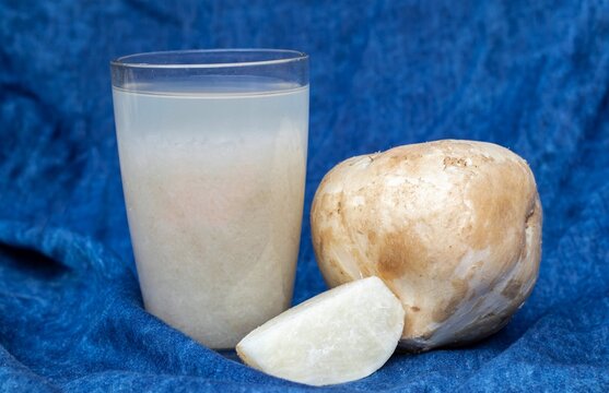 Closeup of Jicama or Mexican Turnip Juice in a Glass with Fruit Isolated on Blue Fabric Background, Also Known as Yam Bean or Shank Aloo