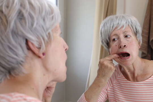 Senior woman checking the inside of her mouth 