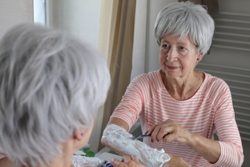 A cute senior woman in her sixties is shaving her forearms