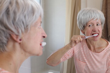 Senior woman feeling pain while brushing her teeth 