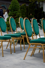 Wedding decor. Ceremony area with emerald chairs with gold legs, side view.