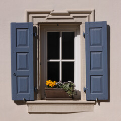 White baroque window with flower pot and blue shutters on a residential house in the old village of Neu-Bamberg, Germany