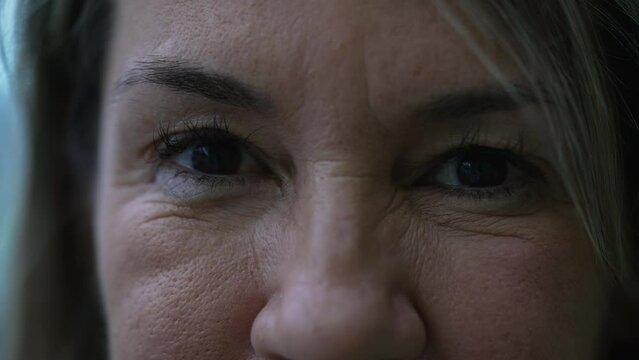 Extreme macro close-up of a woman in her 50s looking at camera with stern serious expression