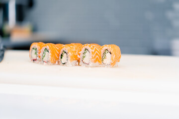 close-up of a philadelphia roll on a white kitchen board in the kitchen of a sushi restaurant